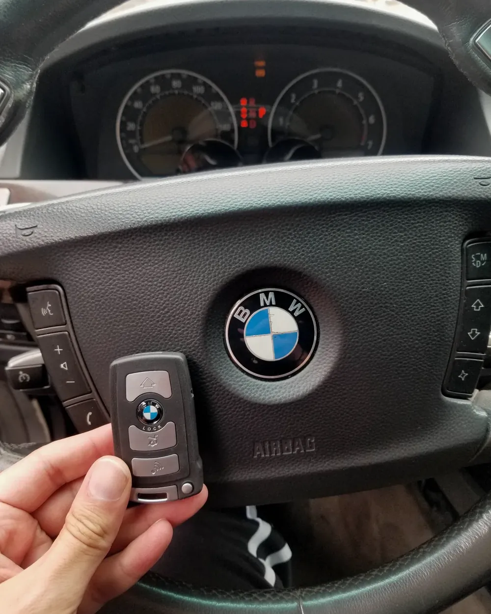 New BMW key held in front of the steering wheel after car key replacement in Nassau County, NY
