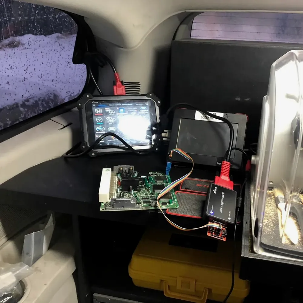 Key programming tools and a key fob circuit board set up in the mobile locksmith van