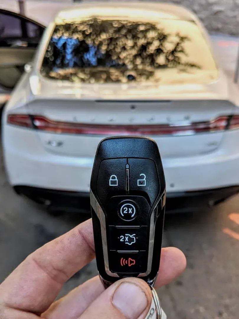 New Lincoln smart key held behind the car in a parking lot