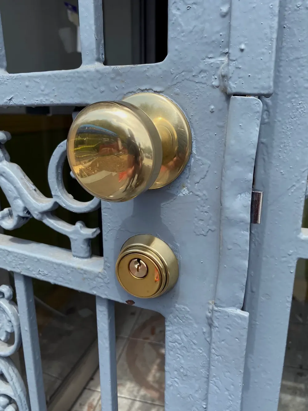 Brass knob and deadbolt on a painted iron security gate