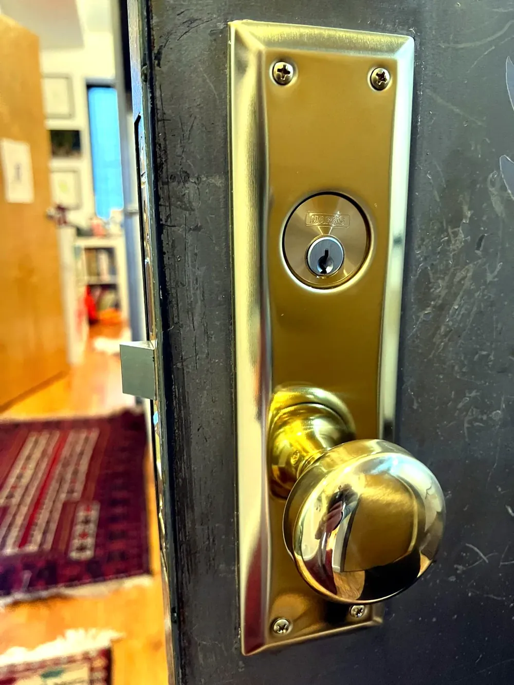 Brass mortise lock with a knob and key cylinder on an older front door