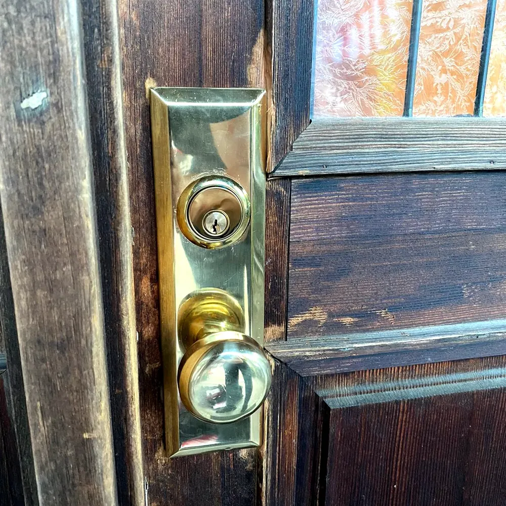 Brass mortise lock with knob and key cylinder on a wood door